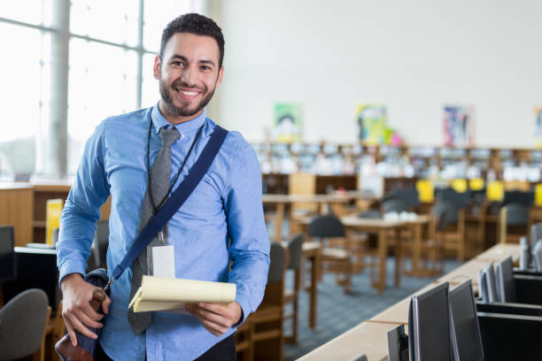 istock Young male school librarian smiles for camera on first day 970321312
