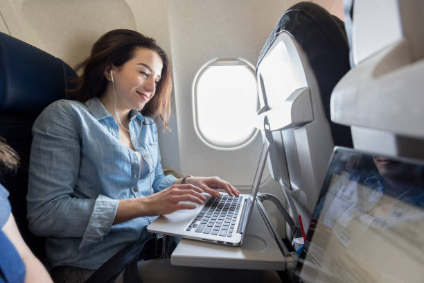 mujer joven usa ordenador portátil en avión comercial - seat belt audio fotografías e imágenes de stock