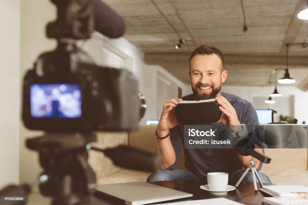 Vlogger making video on vr goggles Technology vlogger reviewing virtual reality glasses. Young man using VR virtual reality goggles for a podcast. Adult Stock Photo