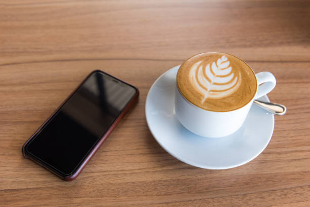 istock Flat white coffee with smart phone on wooden table, Top view 970338990