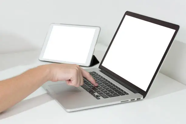 Hand using a laptop with digital tablet on the desk.