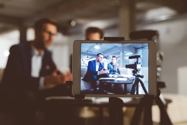 Behind the scenes of a business vlog Two bloggers on digital tablet screen. Businessman with male guest recording a video blog on camera. Behind the scenes of a business vlog. debate stock pictures, royalty-free photos & images