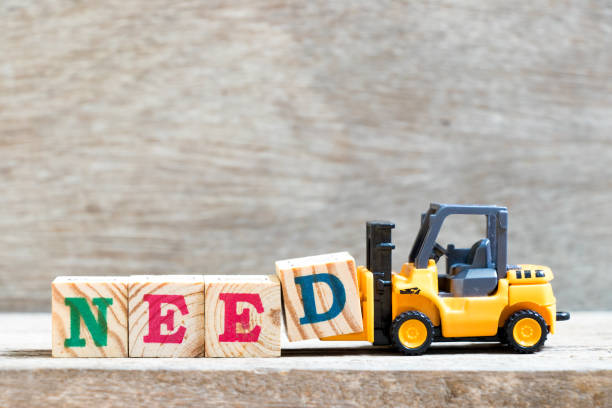 Toy forklift hold letter block D to complete word need on wood background