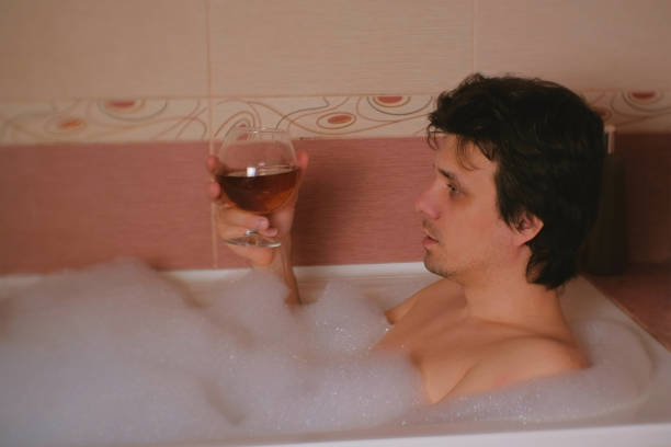 istock Man takes a bath and drinks cognac. Depression and problems in life. 970361388