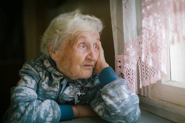 istock Elderly woman sitting at the table looking out the window. 970361836