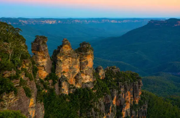 Evening landscape of the Jamison Valley in the Blue Mountains of New South Wales, Australia with the Three Sisters rock formation in the foreground.