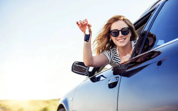 Photo of An attractive woman in a car holds a car key in her hand
