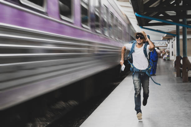 istock Tourist with bag running behind the train, A man runs for a moving wagon, Backpacker hurries for train departing from the station, Journey to the last minute 970374786