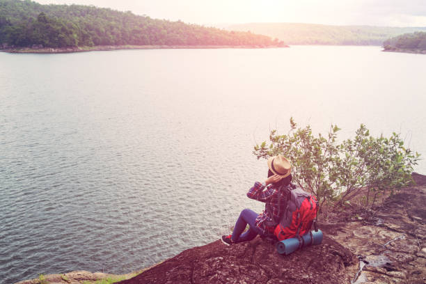 istock Young hipster woman with backpacker sitting on stone enjoying 970381770