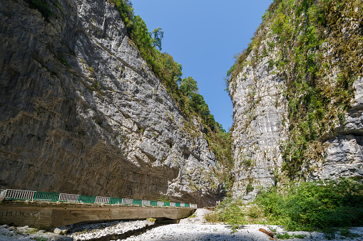 The road and a small bridge between the cliffs at the bottom of the deep canyon