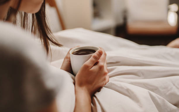 istock Woman holding a coffee cup sitting on bed 970399130