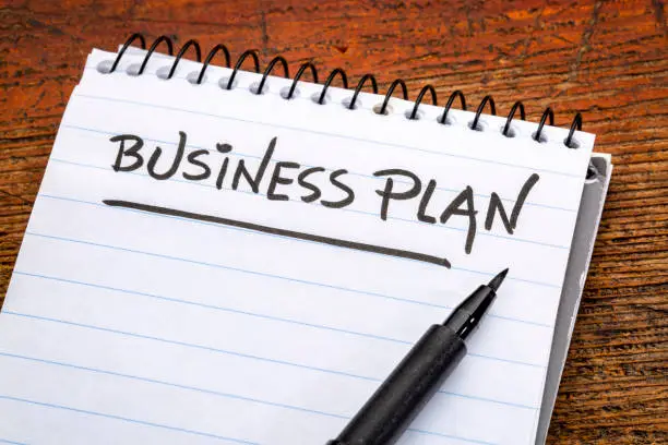 business plan - handwriting in a spiral notebooks against grunge wood