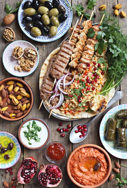 istock Middle eastern, arabic or mediterranean dinner table with grilled lamb kebab, chicken skewers  with roasted vegetables and appetizers variety serving on rustic outdoor table. 970412166