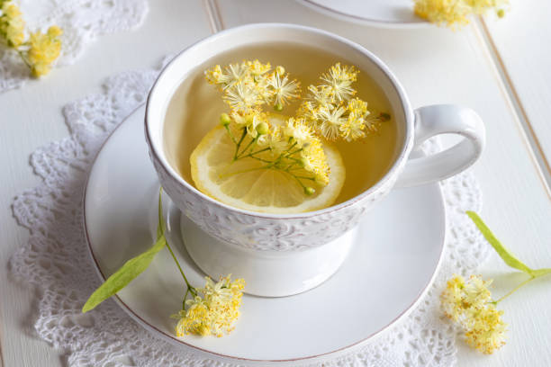 A cup of linden tea with fresh linden flowers A cup of herbal tea with fresh linden flowers and lemon tilia cordata stock pictures, royalty-free photos & images