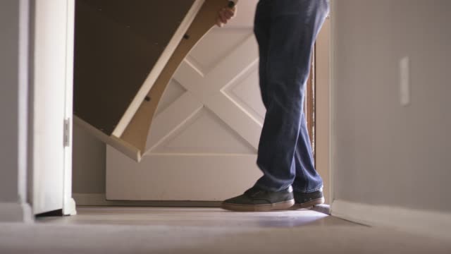 A Group of People Move Furniture Out a Front Door