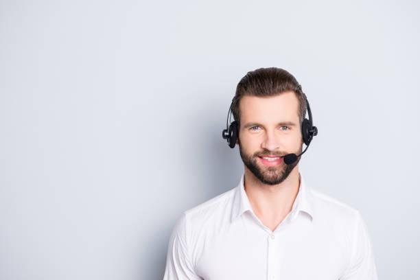 portrait with copy space, empty place for advertisement of stylish, cheerful, harsh, virile operator having headset with microphone on head looking at camera isolated on grey background - hotel reception customer service representative headset receptionist imagens e fotografias de stock