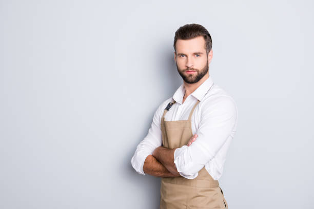 istock Portrait with copyspace, empty place for advertisement of half turned, concentrated attractive barber in shirt having his arms crossed, looking at camera, isolated on grey background 970428150