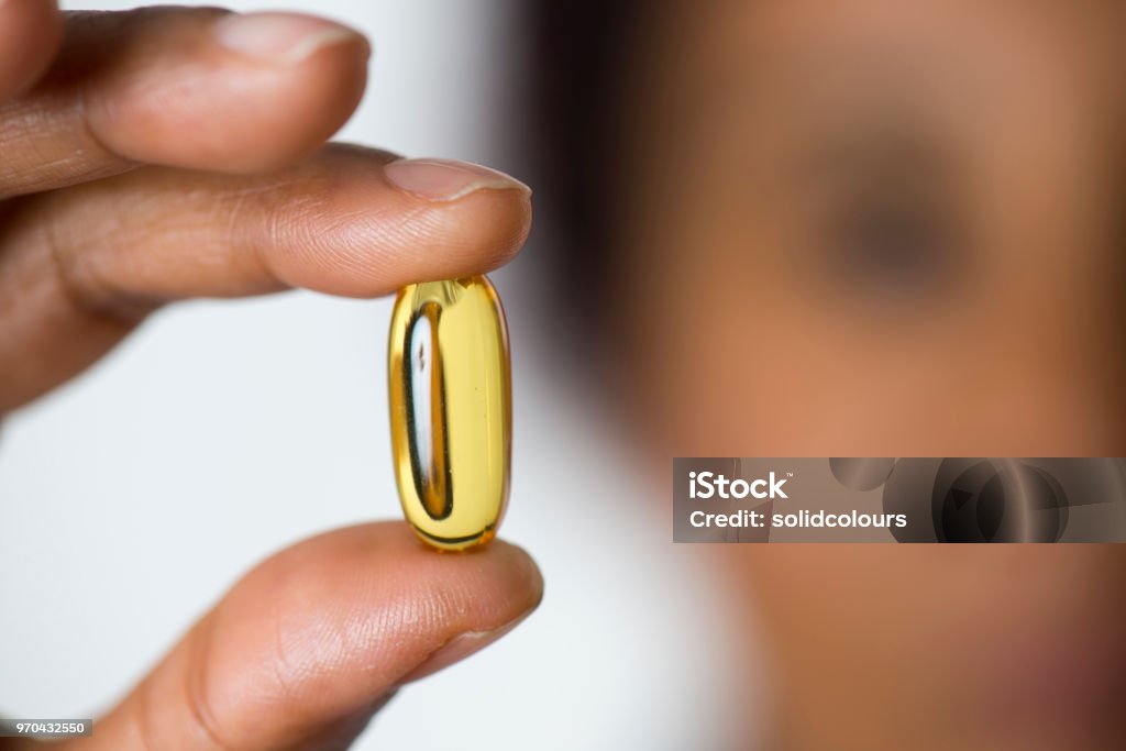 African Woman Showing Pill African woman holding pill, close-up. Omega-3 Stock Photo