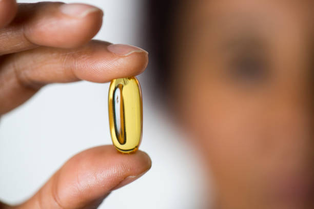 African Woman Showing Pill African woman holding pill, close-up. omega 3 stock pictures, royalty-free photos & images