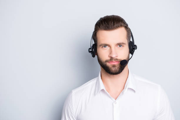 portrait with copy space, empty place for advertisement of  harsh virile operator having headset with microphone on head looking at camera isolated on grey background - hotel reception customer service representative headset receptionist imagens e fotografias de stock