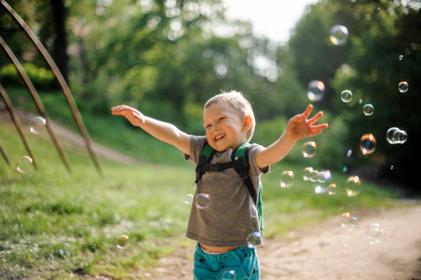 istock Smiling little boy with soap bubbles in summer park on sunny day 970440578