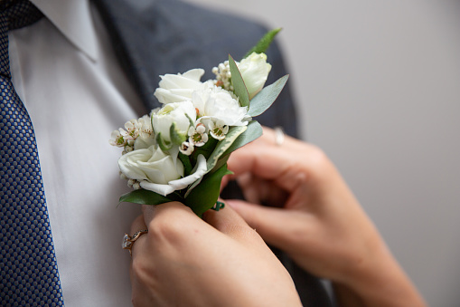 Bride fastens groom boutonniere to buttonhole. wedding