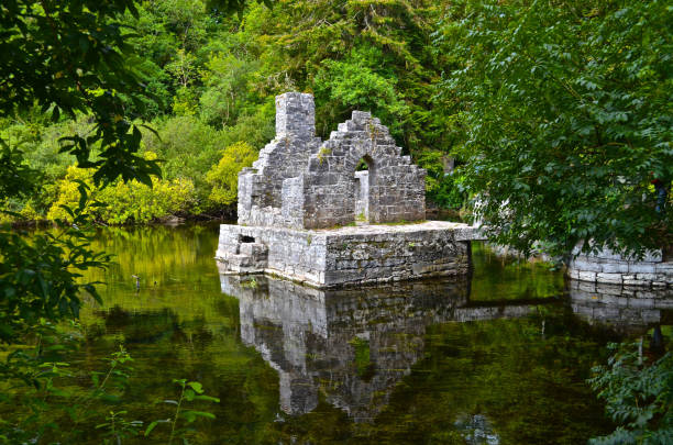 A 13th Century ruin on the Cong River, the Monk's Fishing House, part of Cong Abbey, set in a lush landscape with, in the distance, a weir across the river.  County Mayo, Ireland.