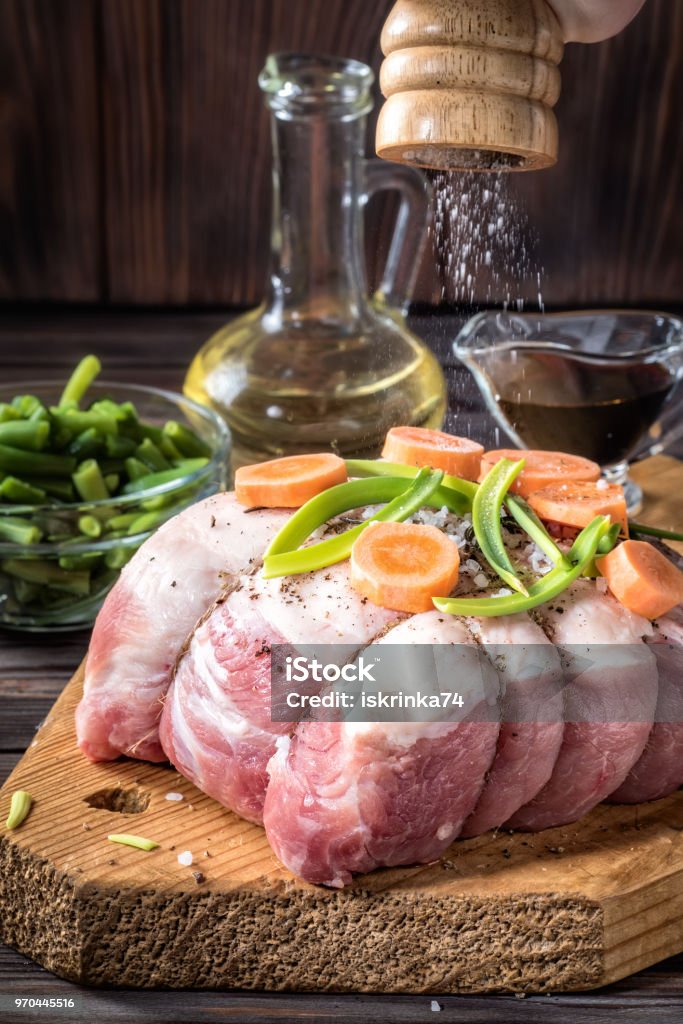 Raw pork chop marinated meat roll with assorted vegetables Raw pork chop meat roll wrapped twine jute marinated strew coarse sea salt shaker mill olive oil with pepper assorted vegetables with carrots green onions On wooden green beans in bowl and soy sauce. Bean Stock Photo