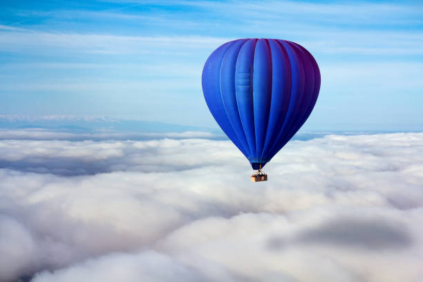 une montgolfière bleu solitaire flotte au-dessus des nuages. leader concept, solitude, réussite, victoire - blowing a balloon photos et images de collection