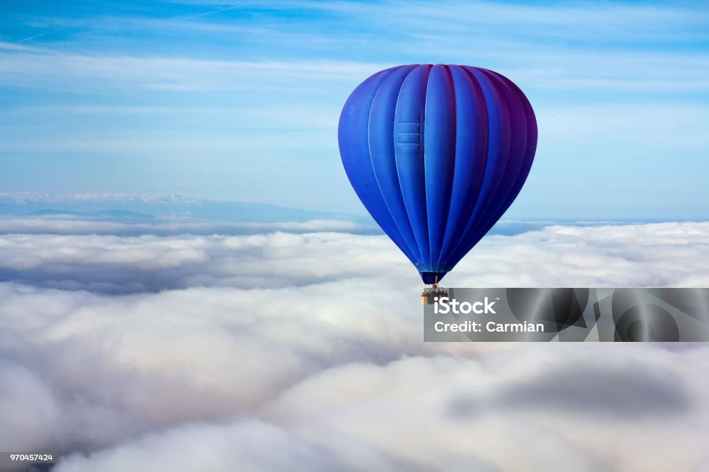 A lonely blue hot air balloon floats above the clouds. Concept leader, success, loneliness, victory Hot Air Balloon Stock Photo