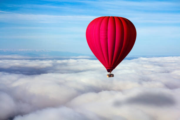 A lonely red hot air balloon floats above the clouds. Concept leader, success, loneliness, victory stock photo