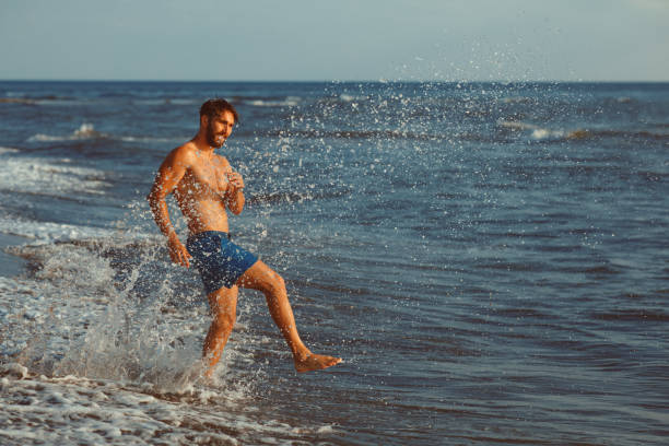 istock Handsome young man having fun on the beach by the sea 970478642
