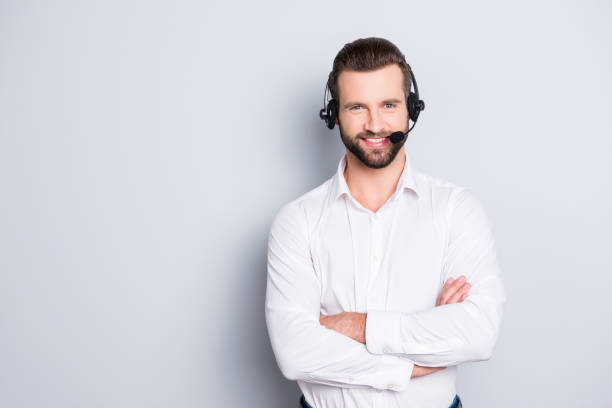 portrait with copyspace, empty place for advertisement of stylish cheerful operator with headset with microphone on head and crossed arms isolated on grey background - hotel reception customer service representative headset receptionist imagens e fotografias de stock