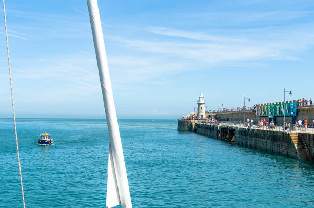 a boat and people by the folkestone harbour arm in summer - horizon over water england uk summer imagens e fotografias de stock