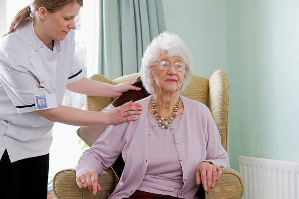若い看護師を老人女性には、快適な椅子 - disablement ストックフォトと画像