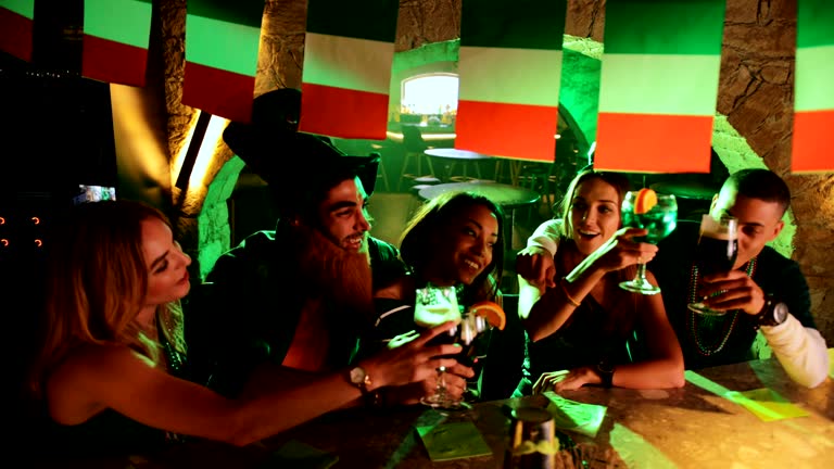 Young multi-ethnic friends having fun, drinking and toasting on Saint Patrick's day in Irish bar
