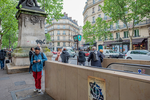 Paris / France - May 14, 2018: A young man stops to check his phone during rush hour commute, at a metro stop in the Saint-Germain des Pres neighborhood.