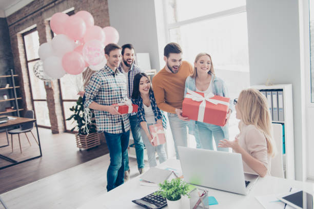 istock Creative, stylish, attractive, cheerful business people making surprise for their impressed, shocked colleague, manager who sitting in modern office with interior, having cases in package with bow 970537490