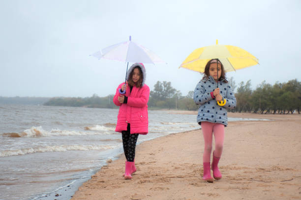 girls with umbrellas on a rainy day on the beach