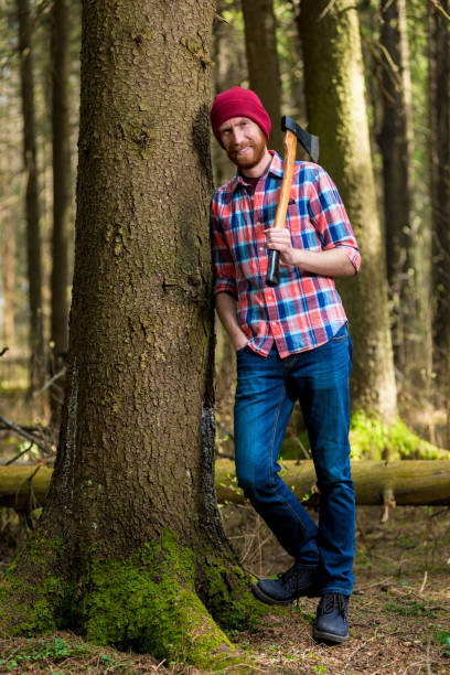 istock a smiling forester with an ax resting, leaning against a tree 970542828