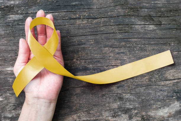 Yellow ribbon symbolic color for Sarcoma Bone cancer, Spina Bifida Awareness Month and suicide prevention on helping hand (isolated with clipping path) Yellow ribbon symbolic color for Sarcoma Bone cancer, Spina Bifida Awareness Month and suicide prevention on helping hand (isolated with clipping path) bladder cancer stock pictures, royalty-free photos & images