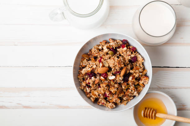 poranna granola z suszonymi owocami, miodem, mlekiem i jagodami na białym drewnianym tle. widok z góry z spacją na kopiowanie - bowl cereal cereal plant granola zdjęcia i obrazy z banku zdjęć