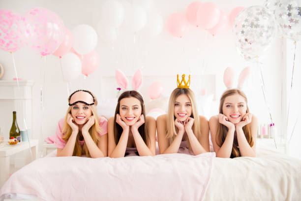 istock Cheerful, charming, pretty, cute, blonde, brunette models laying on stomach looking at camera holding hands near face, wearing gold diadem, rabbit ears, enjoying gathering, meeting indoor 970545384