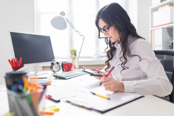 istock A young girl is sitting at the office desk, working with a calculator and documents. 970557238