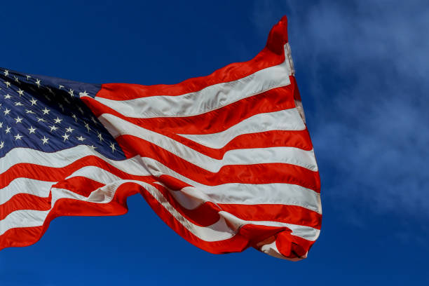 istock The American flag waving in blue sky 970565636