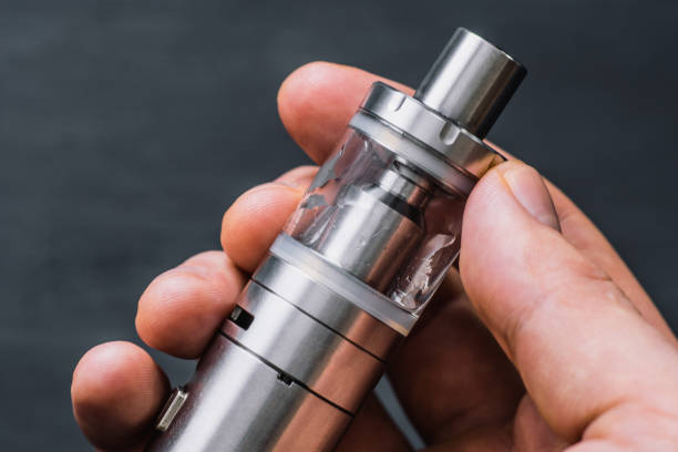 istock smoke at the background. Vape man holding electronic cigarette or vape device with 970569476