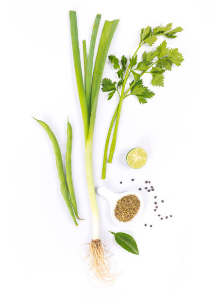 Studio shot and view directly from above of a composition of some vegetables and spices, including spring onion, green beans, celery, cumin, lime and pepper.