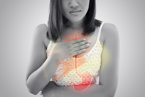 Mujer que sufre de reflujo ácido o acidez estomacal contra fondo gris / Asia personas con síntoma indigestión o Gastritis photo