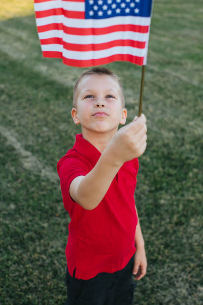 istock Boy looking up at American flag 970647630