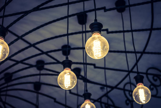 istock Low Angle View Of Illuminated Light Bulbs Hanging Against Sky 970655558